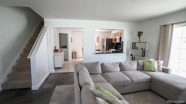 living area with washer and clothes dryer, stairway, tile patterned flooring, and baseboards