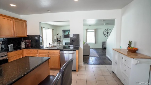 kitchen featuring tasteful backsplash, dark stone countertops, a sink, recessed lighting, and stainless steel dishwasher