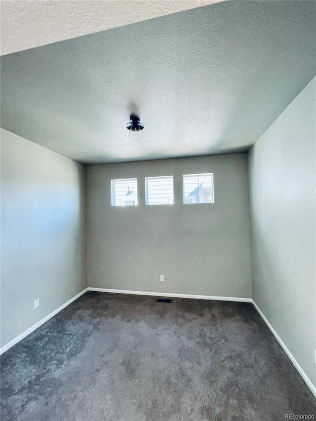 carpeted empty room featuring a textured ceiling