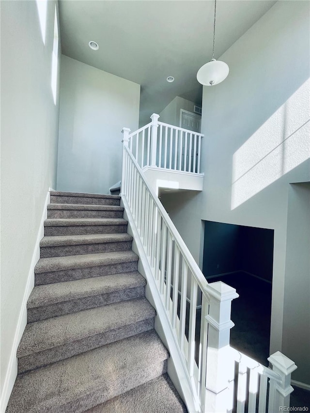 stairway with carpet floors and a high ceiling