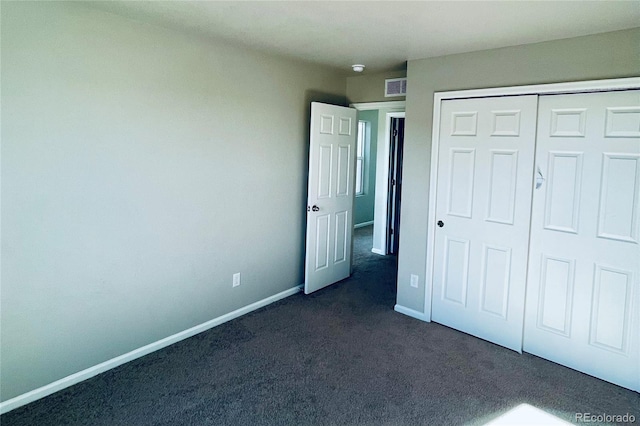 unfurnished bedroom with a closet and dark carpet