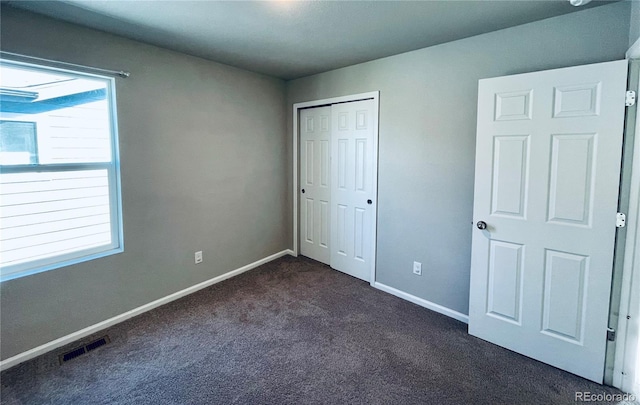 unfurnished bedroom featuring a closet and dark carpet