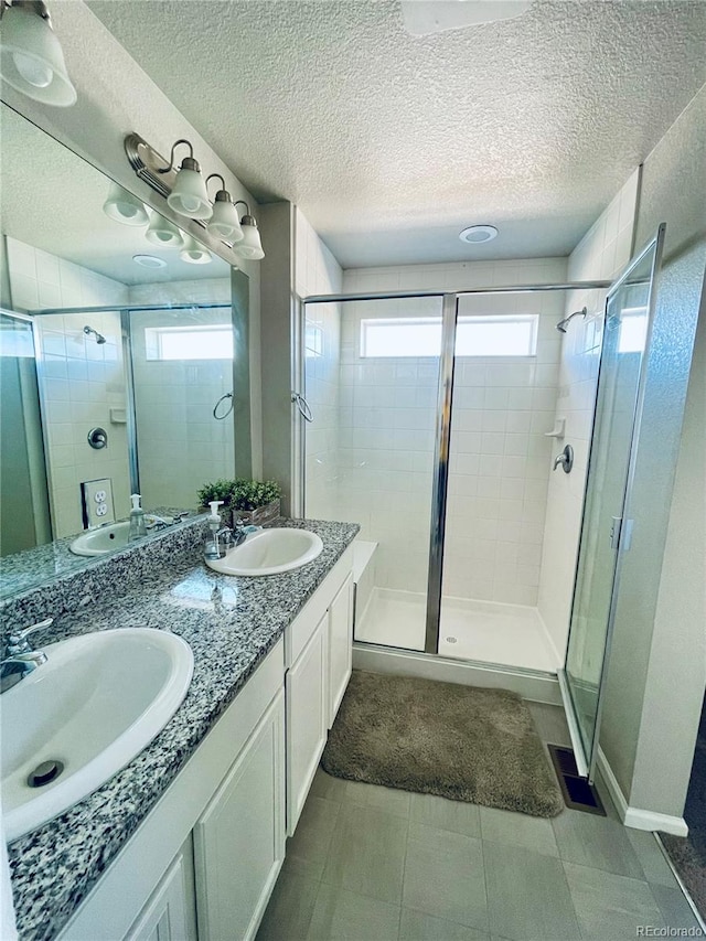 bathroom with vanity, a healthy amount of sunlight, a textured ceiling, and an enclosed shower