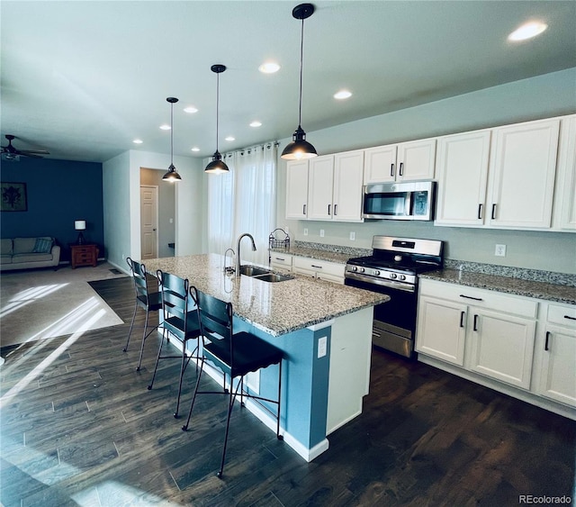 kitchen with white cabinets, a center island with sink, a breakfast bar area, sink, and stainless steel appliances