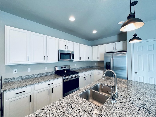 kitchen featuring appliances with stainless steel finishes, sink, pendant lighting, and white cabinets