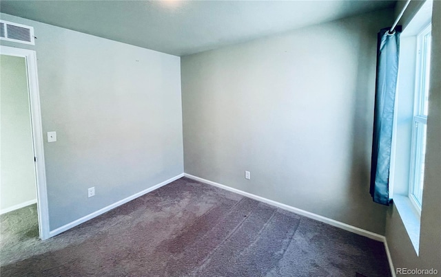 unfurnished room with plenty of natural light and dark colored carpet