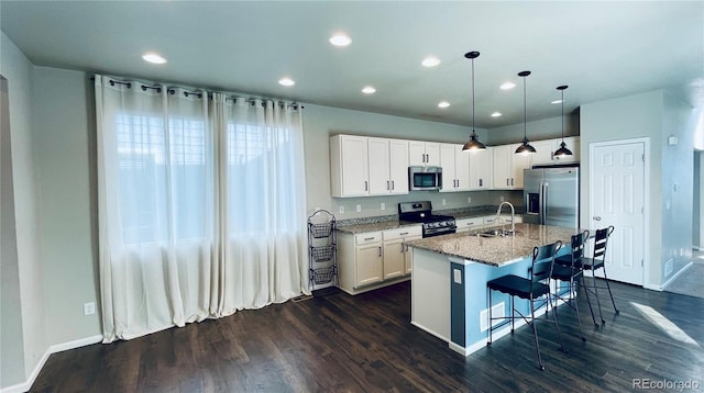 kitchen featuring light stone counters, dark hardwood / wood-style flooring, an island with sink, stainless steel appliances, and decorative light fixtures