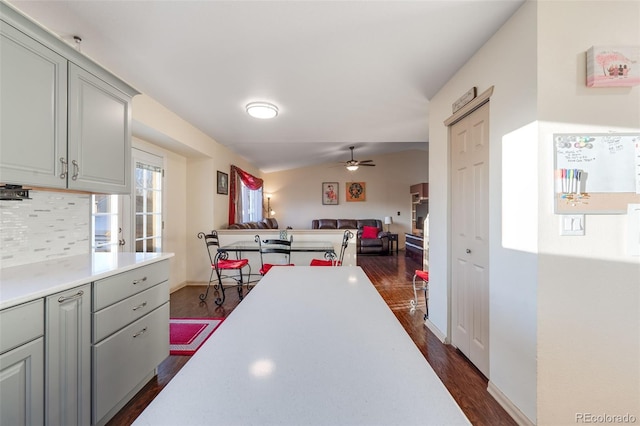 kitchen featuring dark wood-style flooring, a ceiling fan, open floor plan, light countertops, and decorative backsplash