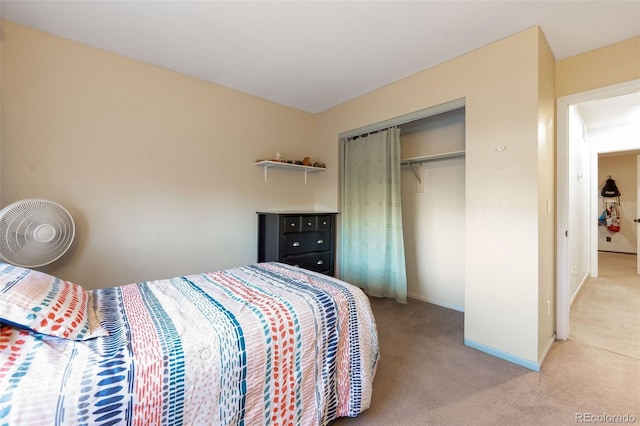 bedroom with a closet, light carpet, and baseboards