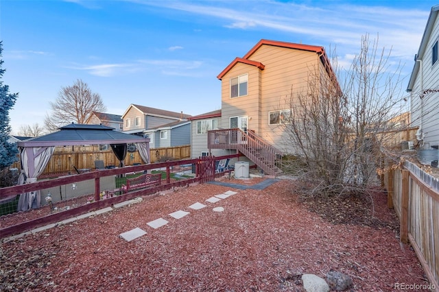 rear view of house featuring a gazebo, stairway, and a fenced backyard