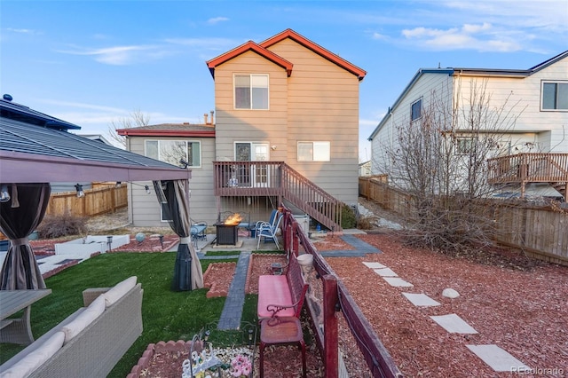 rear view of property featuring a fire pit, a patio, a fenced backyard, stairway, and a yard