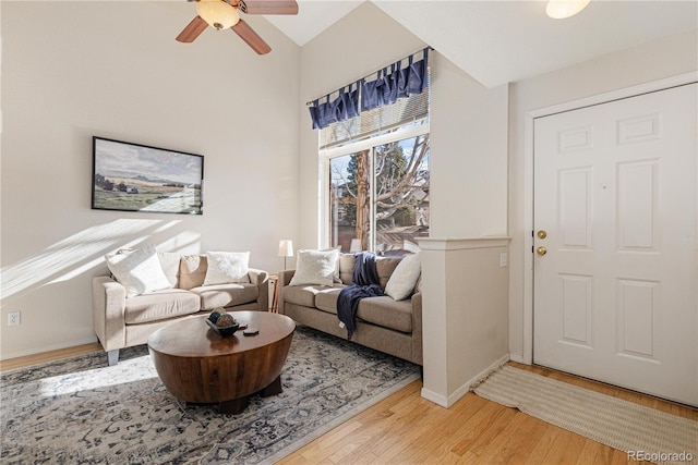 living room with high vaulted ceiling, ceiling fan, and light hardwood / wood-style flooring