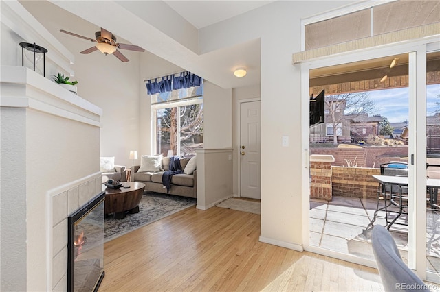 interior space featuring ceiling fan, a fireplace, and light hardwood / wood-style floors