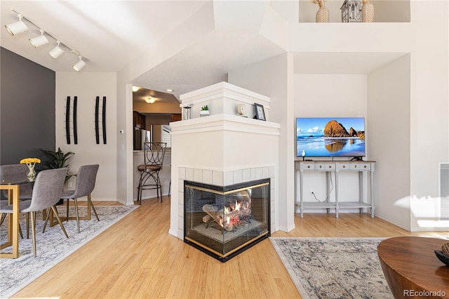 living room featuring rail lighting, hardwood / wood-style floors, and a tile fireplace