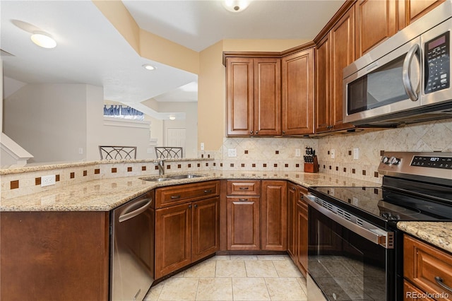 kitchen with stainless steel appliances, light stone countertops, sink, and decorative backsplash