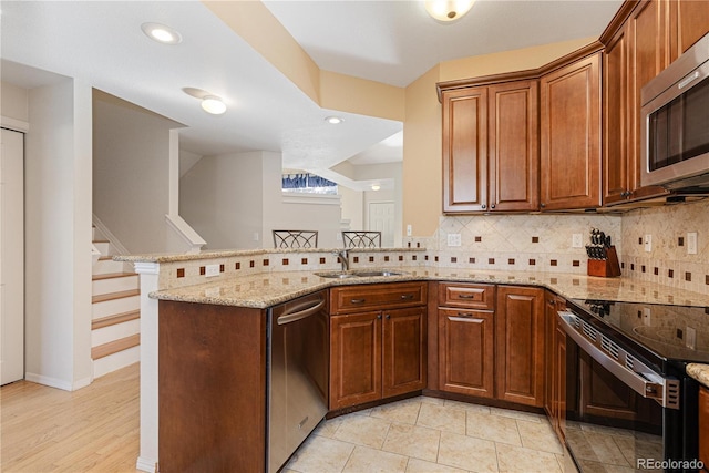 kitchen with sink, appliances with stainless steel finishes, backsplash, light stone countertops, and kitchen peninsula