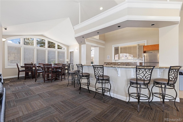 kitchen featuring stainless steel fridge, kitchen peninsula, and a breakfast bar area