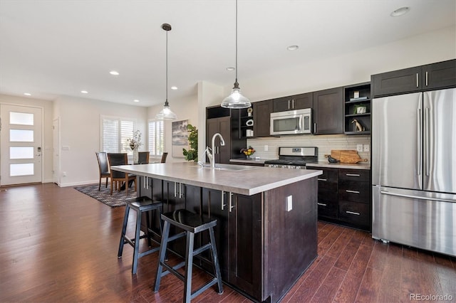 10844 Telluride St, Commerce City, CO 80022 - kitchen featuring appliances with stainless steel finishes, open shelves, dark wood-style flooring, tasteful backsplash, and light countertops