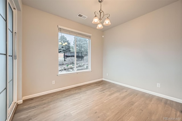 unfurnished room featuring visible vents, baseboards, wood finished floors, and a notable chandelier