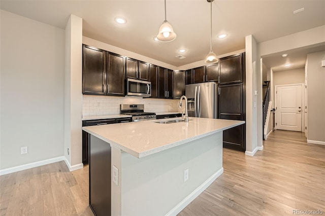 kitchen with baseboards, appliances with stainless steel finishes, a sink, and light wood-style floors