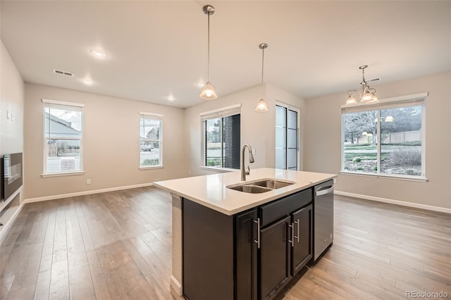 kitchen with a sink, light wood finished floors, light countertops, stainless steel dishwasher, and visible vents
