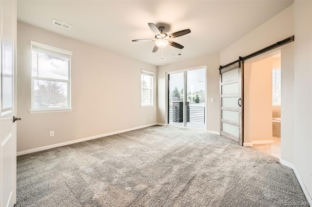 unfurnished bedroom with visible vents, a barn door, carpet, and access to outside