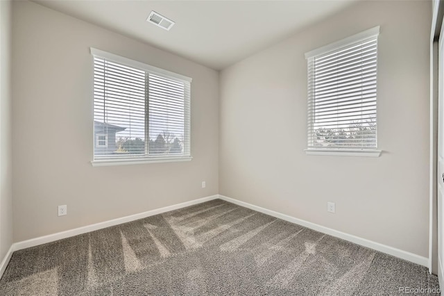 empty room with carpet floors, baseboards, and visible vents