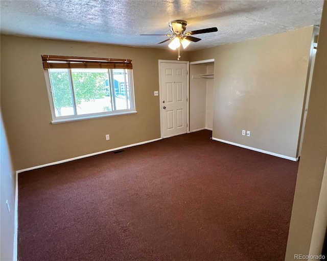 spare room featuring ceiling fan, dark carpet, and a textured ceiling