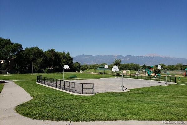 view of community with a mountain view, basketball court, a lawn, and a playground