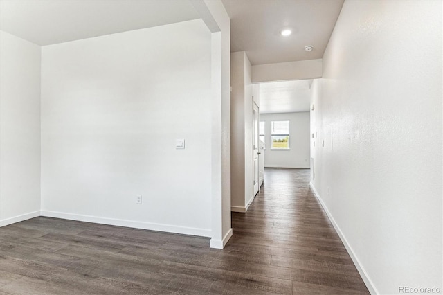 hallway featuring dark wood finished floors and baseboards