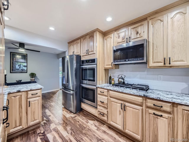 kitchen with light stone countertops, light brown cabinetry, stainless steel appliances, ceiling fan, and hardwood / wood-style floors