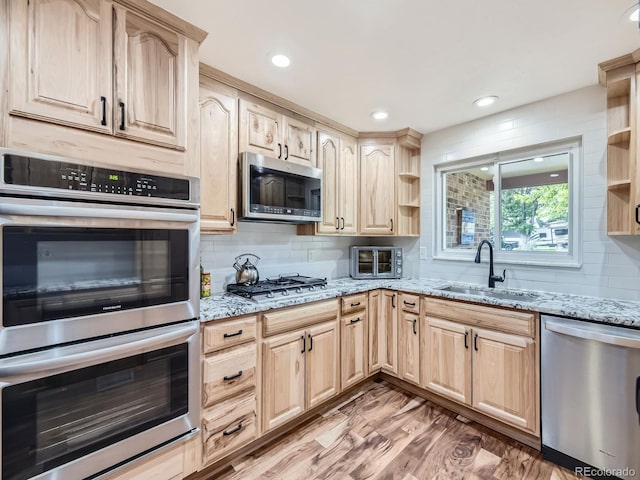 kitchen featuring light brown cabinetry, sink, wood-type flooring, and stainless steel appliances