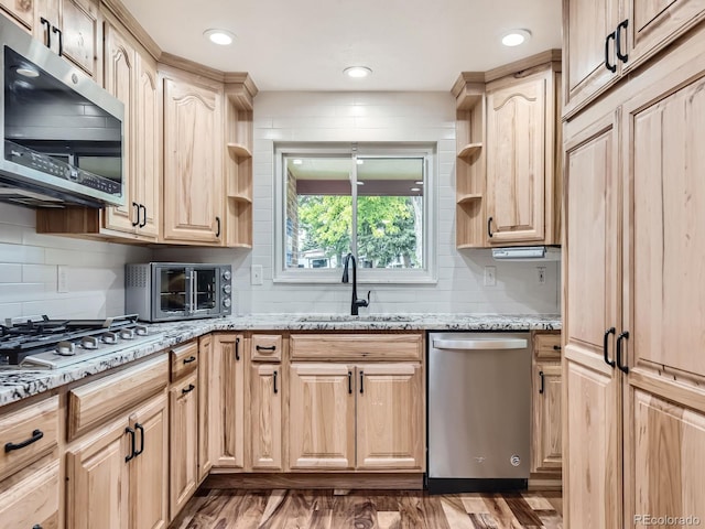 kitchen featuring appliances with stainless steel finishes, dark hardwood / wood-style flooring, light brown cabinetry, light stone counters, and sink