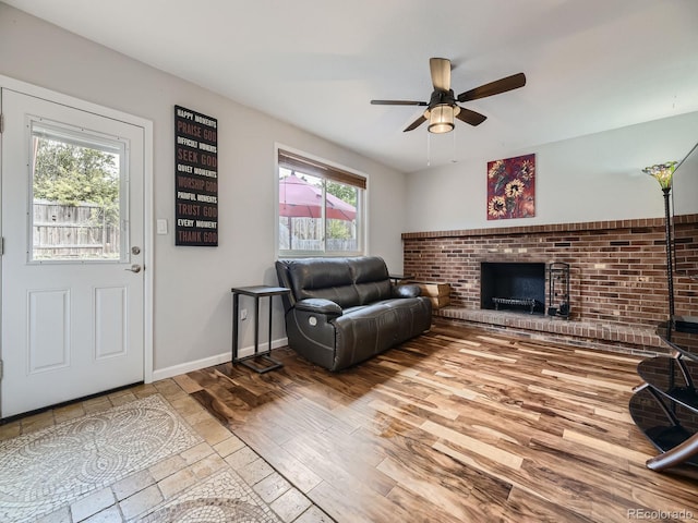 living room with hardwood / wood-style floors, a brick fireplace, ceiling fan, and a healthy amount of sunlight