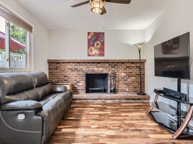 living room featuring hardwood / wood-style floors, a brick fireplace, and ceiling fan