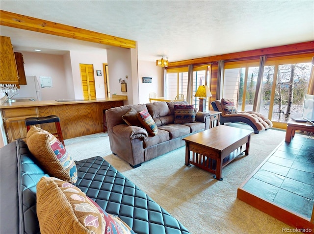 carpeted living room with a sink and beam ceiling