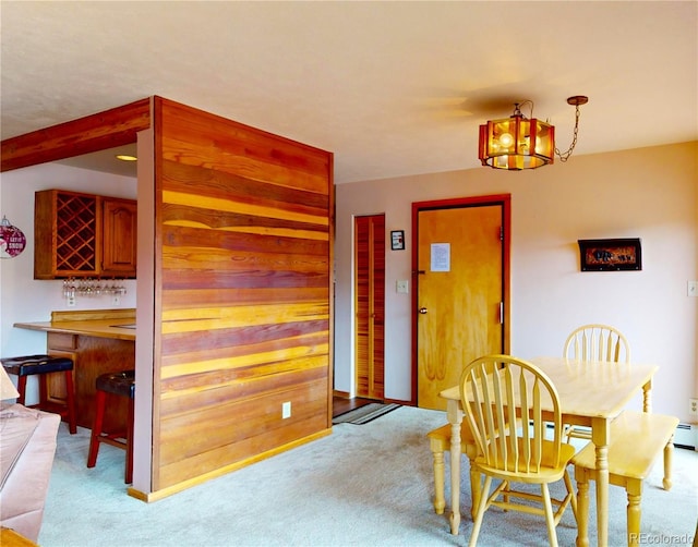 dining room featuring light carpet and a bar