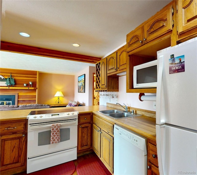 kitchen with a sink, brown cabinets, white appliances, and recessed lighting