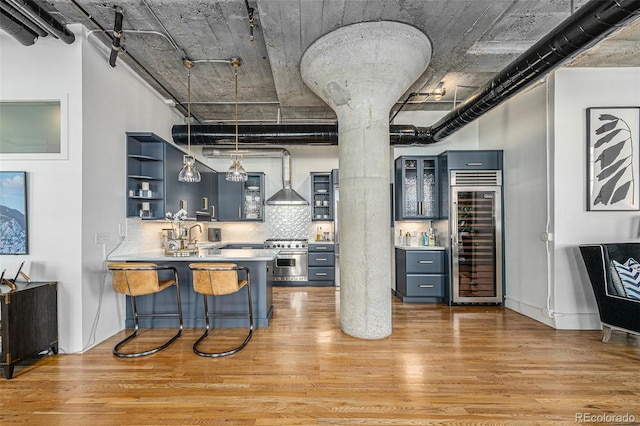 1863 Wazee St Unit 4E, Denver, CO 80202 - kitchen featuring beverage cooler, high end stainless steel range, open shelves, light wood-style floors, and glass insert cabinets