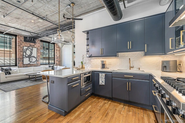 1863 Wazee St Unit 4E, Denver, CO 80202 - kitchen featuring high quality stove, a peninsula, light wood-style flooring, light countertops, and a high ceiling