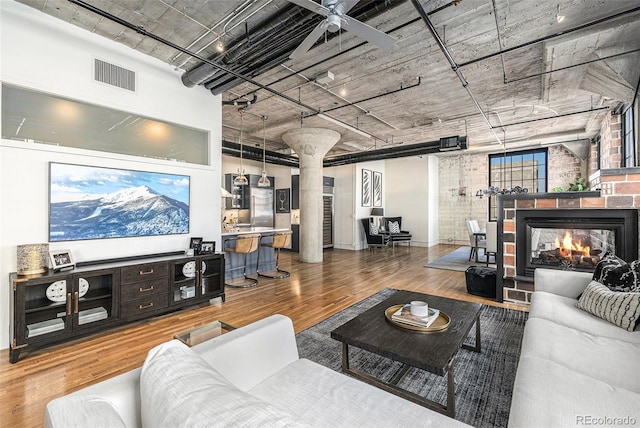 1863 Wazee St Unit 4E, Denver, CO 80202 - living room featuring ornate columns, wood finished floors, a fireplace, and ceiling fan