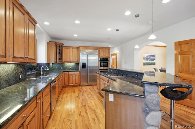 30 Carroll Ct, Black Hawk, CO 80422 - kitchen with appliances with stainless steel finishes, a sink, brown cabinets, a breakfast bar area, and light wood-type flooring