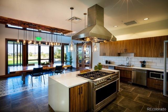 27664 E Byers Ave, Aurora, CO 80018 - kitchen featuring stainless steel appliances, a sink, island range hood, brown cabinetry, and light countertops