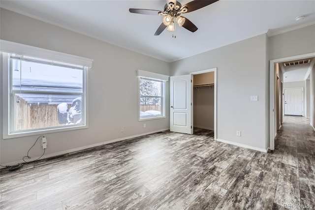 unfurnished bedroom featuring ceiling fan, a closet, a spacious closet, and hardwood / wood-style flooring