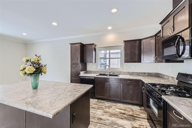 kitchen featuring light wood-type flooring, ornamental molding, sink, black appliances, and a kitchen island