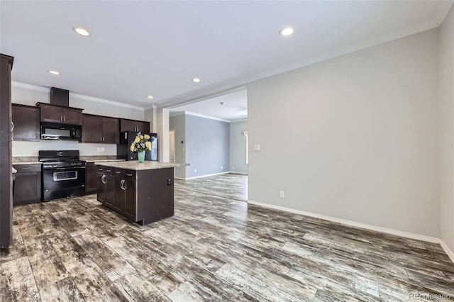 kitchen with dark hardwood / wood-style flooring, a center island, ornamental molding, and black appliances