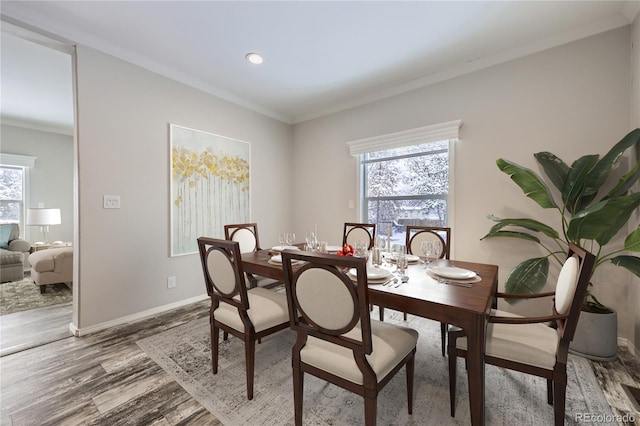 dining space with wood-type flooring, ornamental molding, and a wealth of natural light