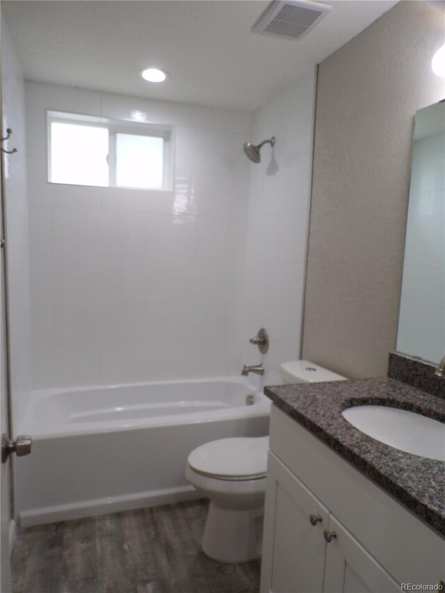 full bathroom with hardwood / wood-style flooring, vanity, toilet, and tiled shower / bath