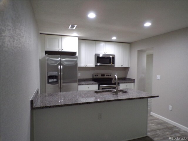 kitchen featuring dark stone counters, white cabinets, sink, dark hardwood / wood-style floors, and appliances with stainless steel finishes