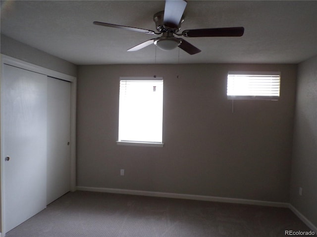 unfurnished bedroom featuring ceiling fan, a closet, carpet floors, and multiple windows